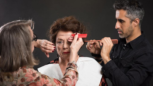 Professional hair stylists making final touches to actress' wig on a film set